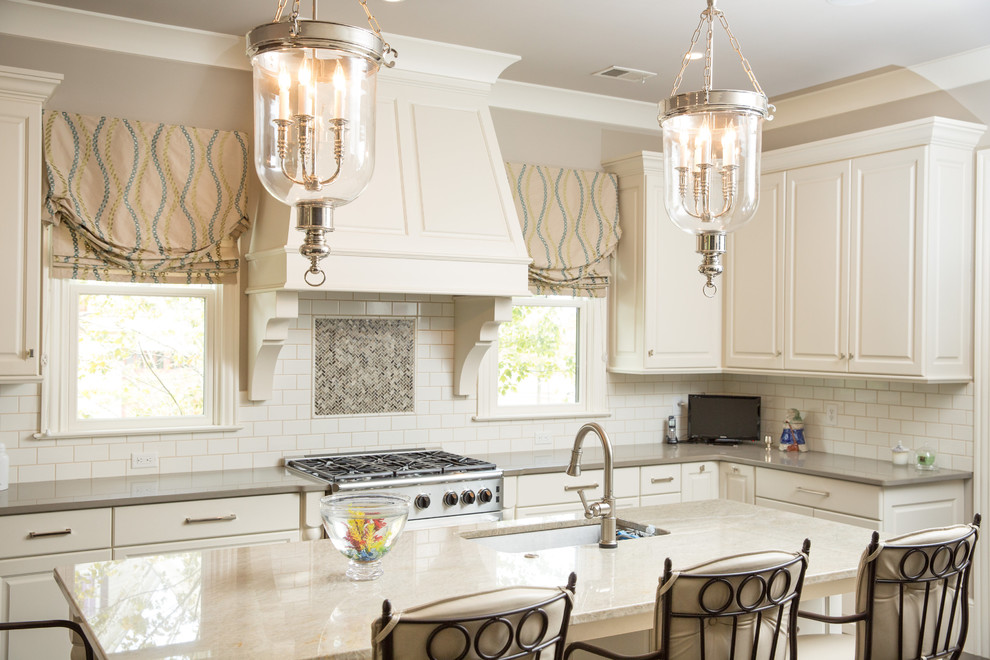 Kitchen - large transitional l-shaped kitchen idea in Charleston with an undermount sink, raised-panel cabinets, white cabinets, granite countertops, white backsplash, subway tile backsplash, stainless steel appliances and an island