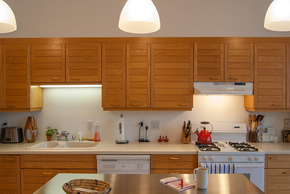 На фото: кухня в стиле лофт с накладной мойкой, фасадами с филенкой типа жалюзи, фасадами цвета дерева среднего тона и белой техникой