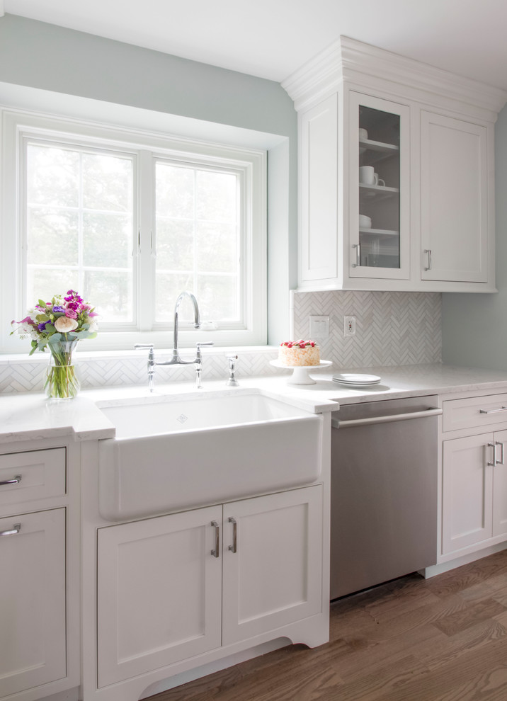 Eat-in kitchen - mid-sized traditional l-shaped medium tone wood floor and brown floor eat-in kitchen idea in Boston with a farmhouse sink, beaded inset cabinets, white cabinets, quartz countertops, white backsplash, marble backsplash, stainless steel appliances and no island