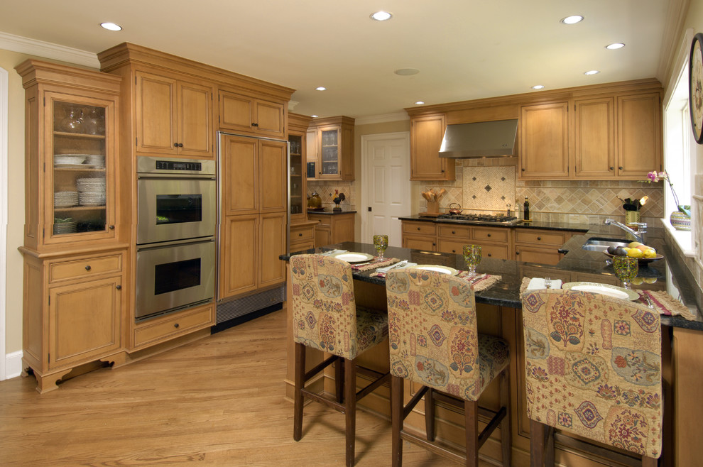 Kitchen - traditional kitchen idea in DC Metro with a double-bowl sink, recessed-panel cabinets, medium tone wood cabinets, beige backsplash and paneled appliances