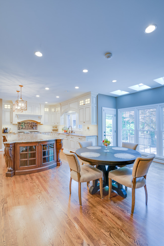 This is an example of a large contemporary kitchen/diner in DC Metro with a built-in sink, white cabinets, granite worktops, light hardwood flooring and an island.