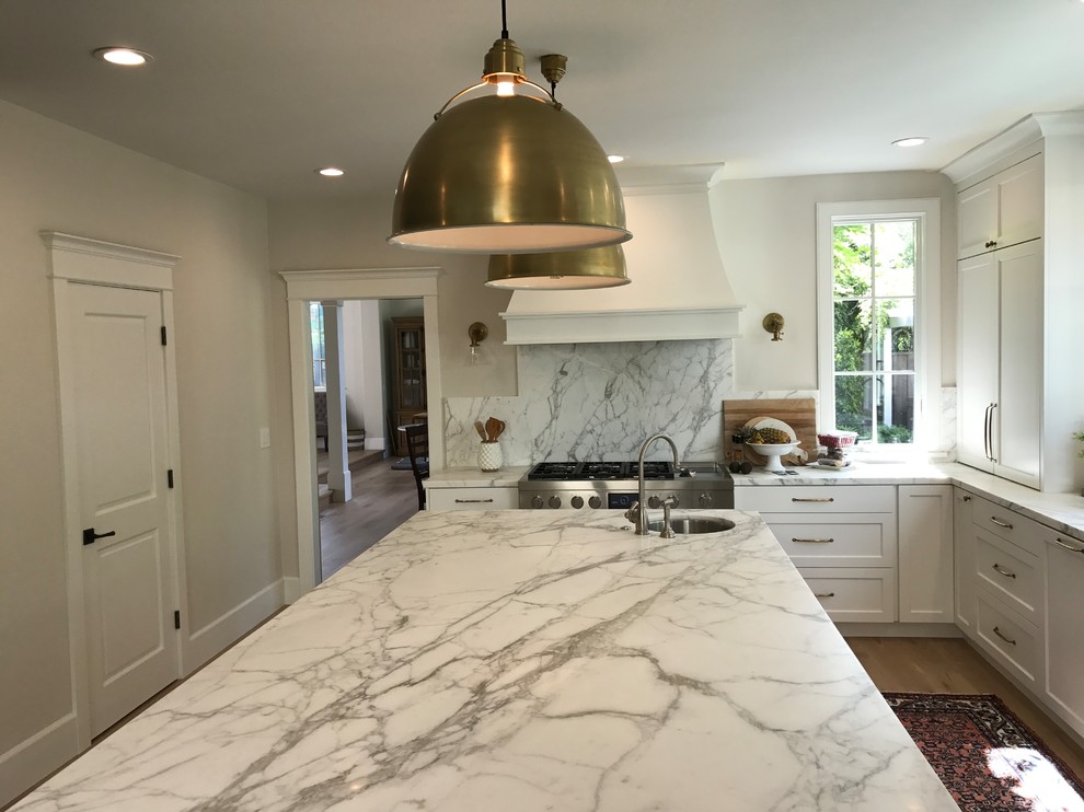 This is an example of a large classic u-shaped kitchen/diner in San Francisco with a submerged sink, recessed-panel cabinets, white cabinets, marble worktops, grey splashback, stone slab splashback, stainless steel appliances, light hardwood flooring, an island, beige floors and grey worktops.