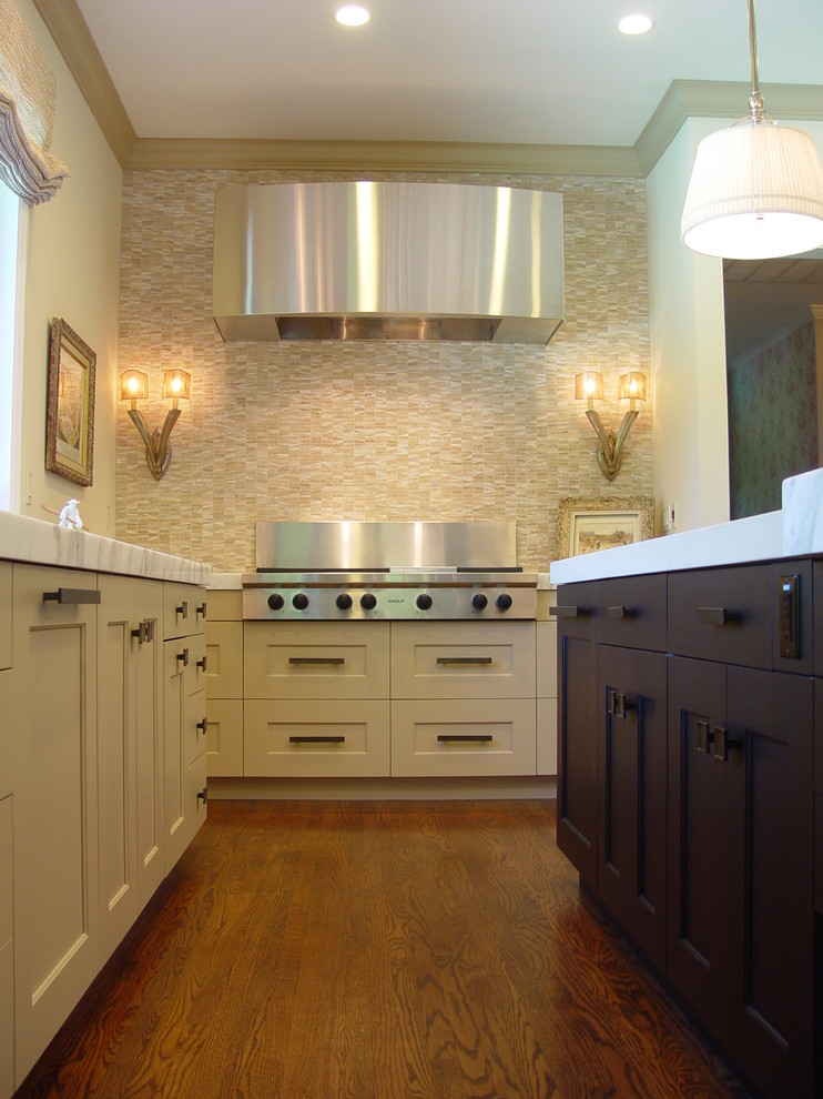 Modelo de cocina tradicional renovada con electrodomésticos de acero inoxidable, armarios con paneles empotrados, puertas de armario amarillas, salpicadero beige y salpicadero de azulejos en listel