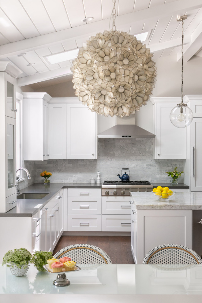 Klassisk inredning av ett stort flerfärgad flerfärgat kök, med en undermonterad diskho, luckor med infälld panel, vita skåp, bänkskiva i kvarts, grått stänkskydd, stänkskydd i marmor, integrerade vitvaror, mörkt trägolv, en köksö och brunt golv