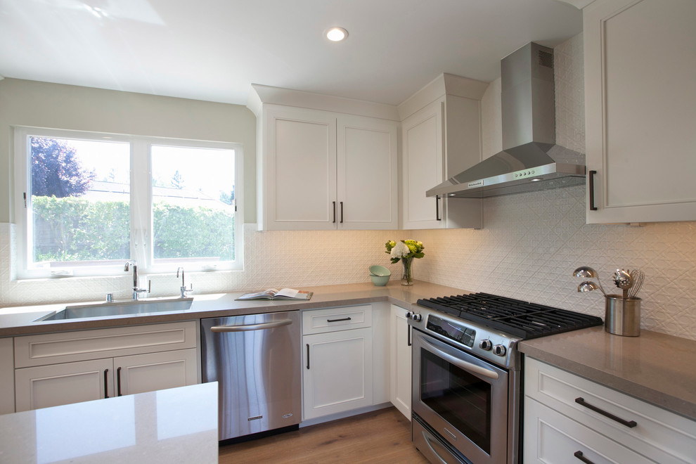 Eat-in kitchen - mid-sized transitional l-shaped light wood floor eat-in kitchen idea in San Francisco with an undermount sink, recessed-panel cabinets, white cabinets, quartz countertops, white backsplash, ceramic backsplash, stainless steel appliances and an island