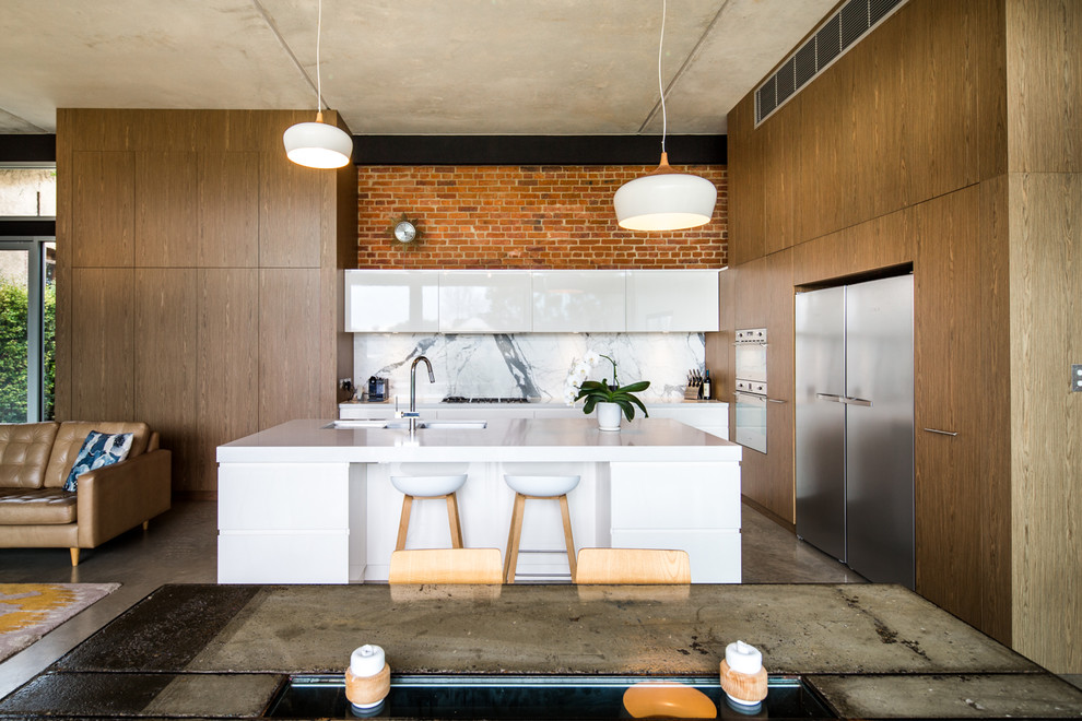 Bild på ett mycket stort industriellt kök, med en undermonterad diskho, släta luckor, vita skåp, bänkskiva i kvarts, flerfärgad stänkskydd, stänkskydd i marmor, rostfria vitvaror, betonggolv, en köksö och grått golv