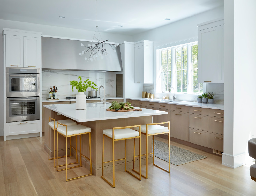 Inspiration for a large transitional u-shaped light wood floor and brown floor open concept kitchen remodel in New York with flat-panel cabinets, white cabinets, quartzite countertops, white backsplash, porcelain backsplash, stainless steel appliances, an island and white countertops