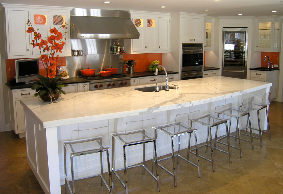 Example of a mid-sized minimalist single-wall ceramic tile eat-in kitchen design in New York with beaded inset cabinets, white cabinets, marble countertops, orange backsplash, stainless steel appliances, an island, an undermount sink and glass tile backsplash