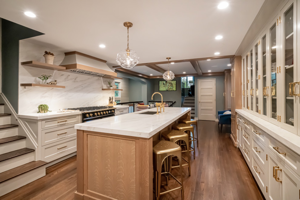 Photo of a large traditional galley kitchen/diner in New York with a submerged sink, white cabinets, marble worktops, white splashback, marble splashback, medium hardwood flooring, an island, brown floors, white worktops, shaker cabinets and integrated appliances.