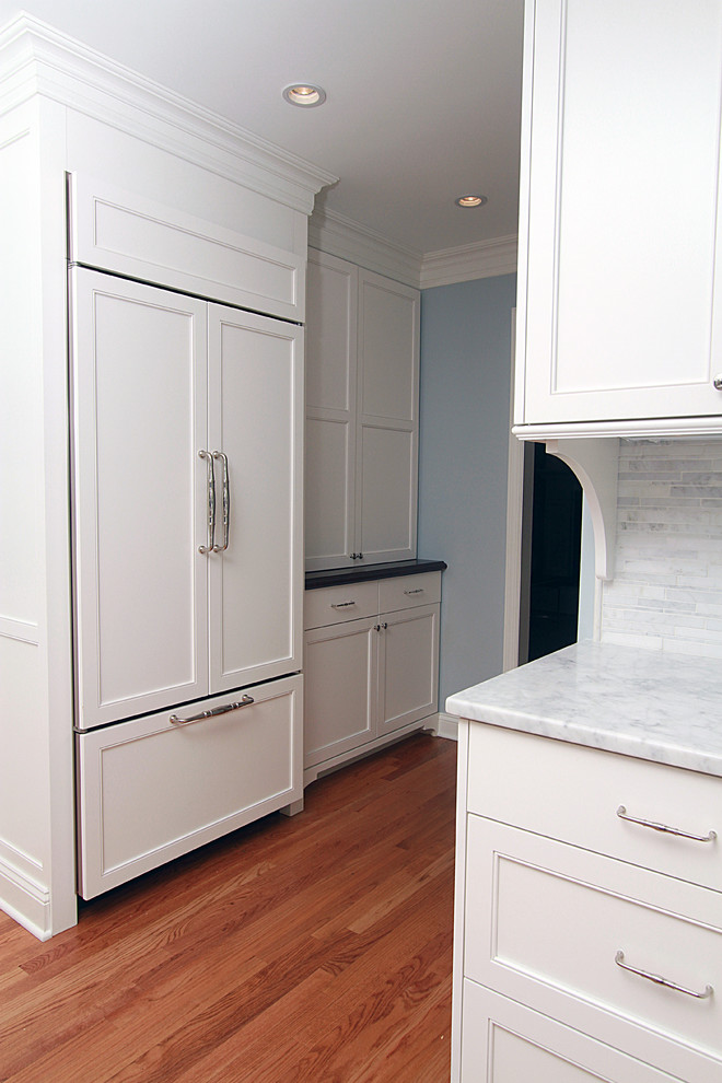 ニューヨークにある中くらいなトラディショナルスタイルのおしゃれなアイランドキッチン (落し込みパネル扉のキャビネット、白いキャビネット、木材カウンター、シルバーの調理設備、無垢フローリング) の写真