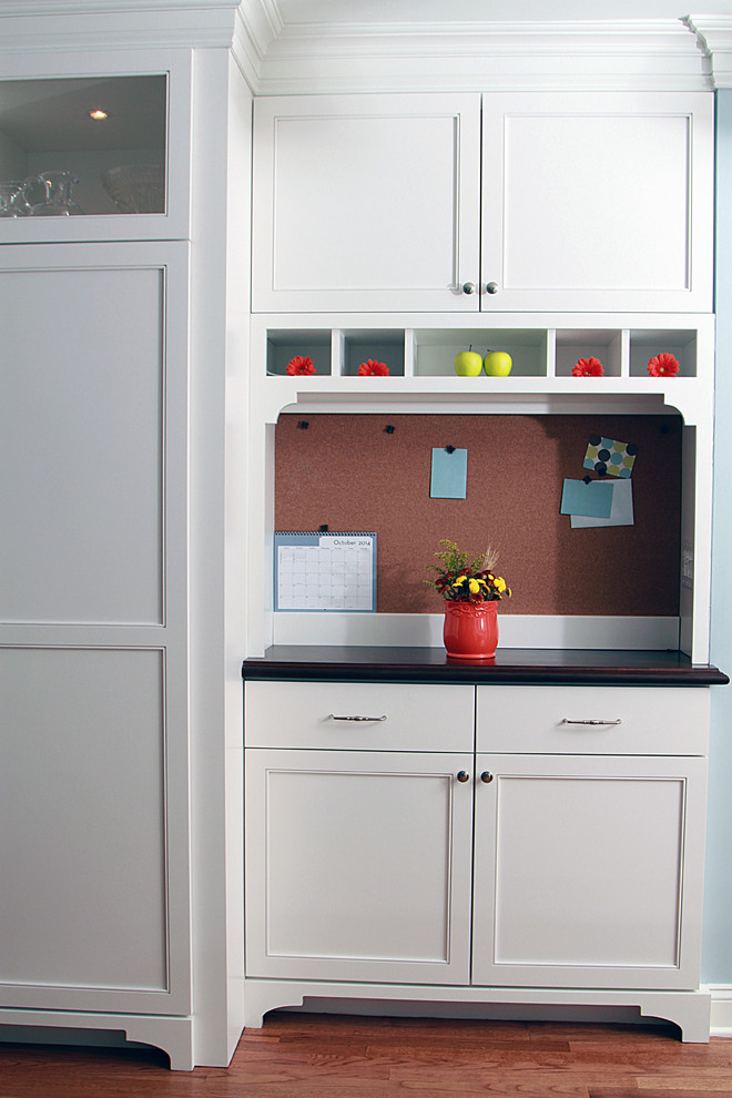 Exemple d'une cuisine chic de taille moyenne avec un placard avec porte à panneau encastré, des portes de placard blanches, un plan de travail en bois, un électroménager en acier inoxydable, un sol en bois brun et îlot.