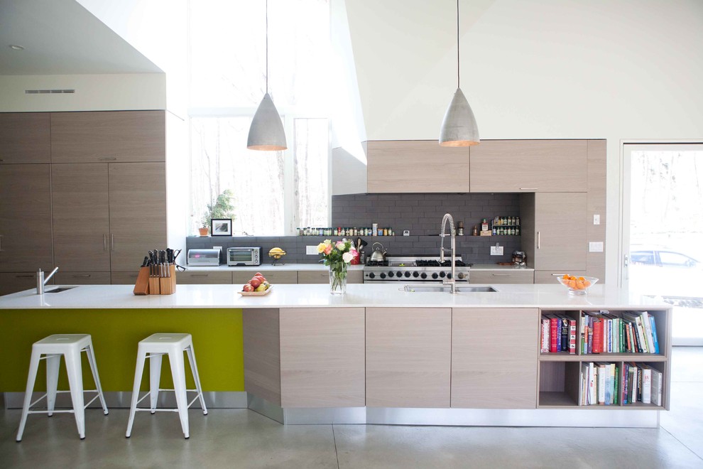 На фото: параллельная кухня в стиле модернизм с врезной мойкой, плоскими фасадами, светлыми деревянными фасадами, серым фартуком и техникой из нержавеющей стали с