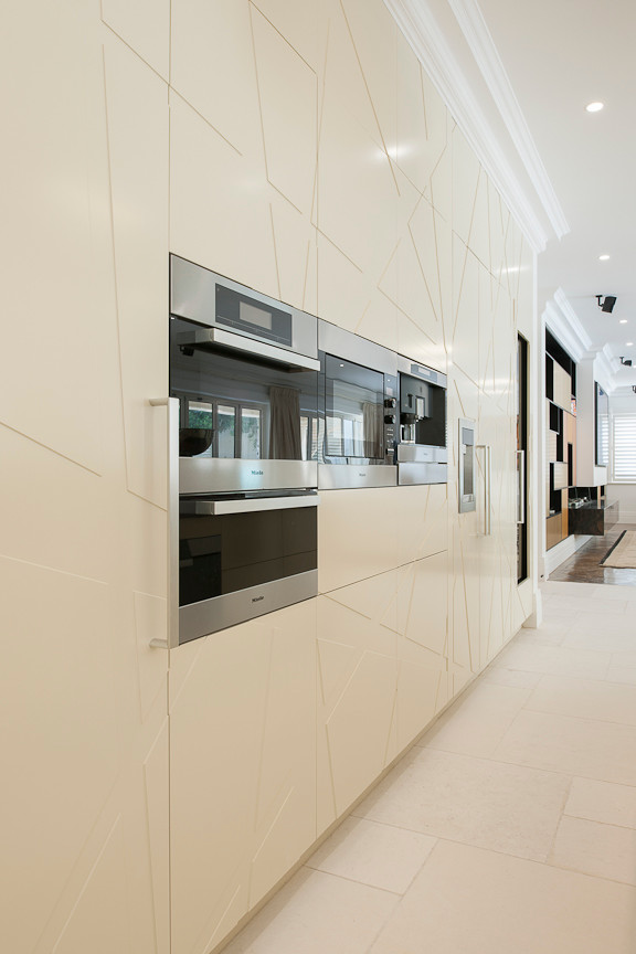 Immagine di un'ampia cucina minimal con ante lisce, ante beige, elettrodomestici neri e pavimento in pietra calcarea