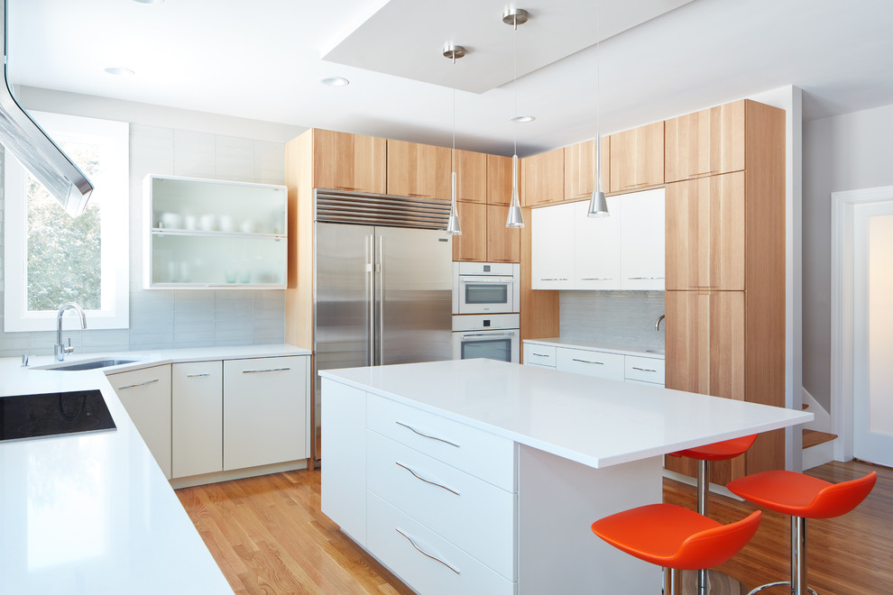 Bild på ett mellanstort funkis vit vitt kök, med en enkel diskho, släta luckor, vita skåp, bänkskiva i kvarts, stänkskydd i glaskakel, vita vitvaror, mellanmörkt trägolv, en köksö och grått stänkskydd