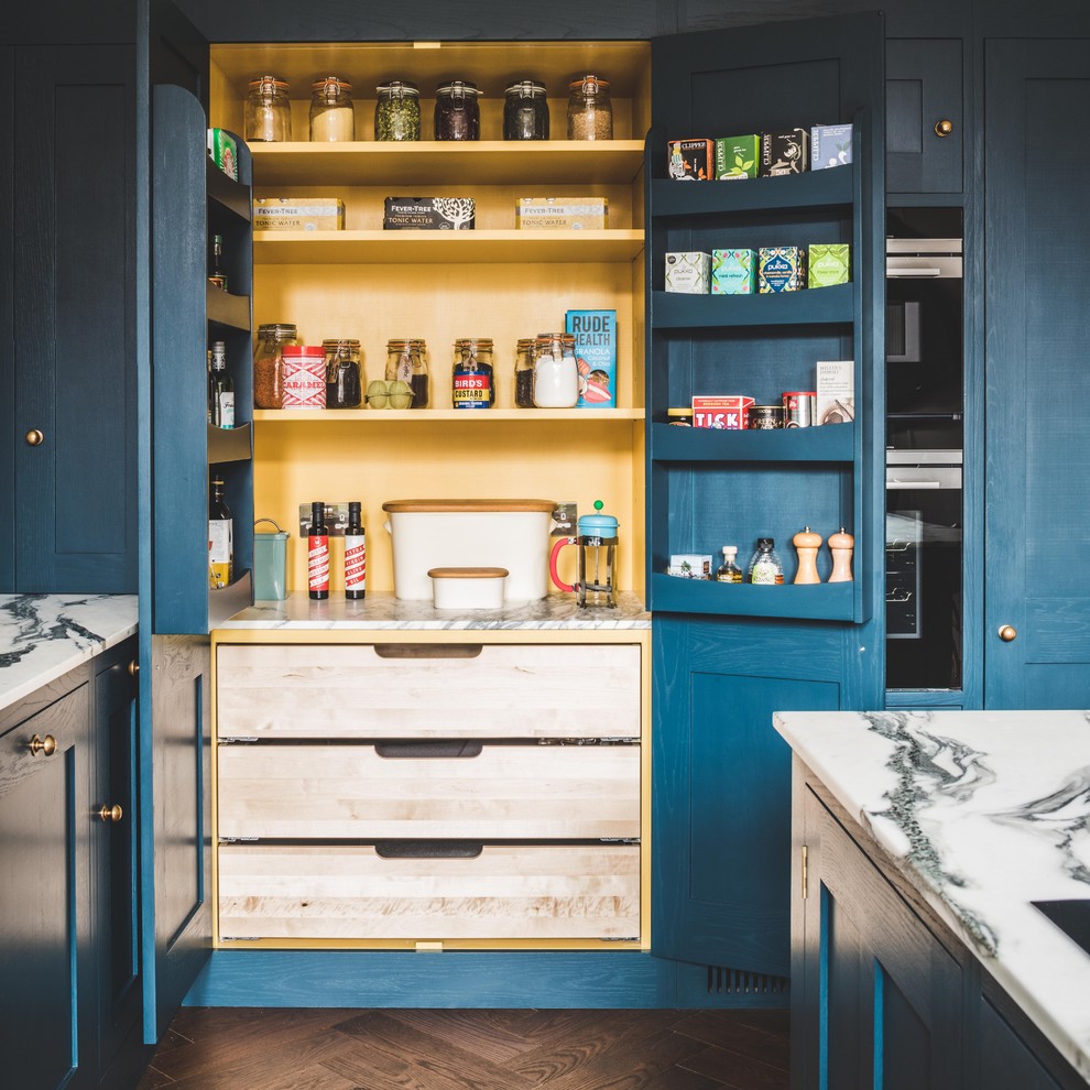 Photo of a large contemporary l-shaped kitchen/diner in Other with a belfast sink, shaker cabinets, blue cabinets, marble worktops, blue splashback, cement tile splashback, stainless steel appliances, dark hardwood flooring, an island and brown floors.