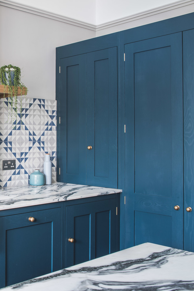 Inredning av ett modernt stort kök, med en rustik diskho, skåp i shakerstil, blå skåp, marmorbänkskiva, blått stänkskydd, stänkskydd i cementkakel, rostfria vitvaror, mörkt trägolv, en köksö och brunt golv