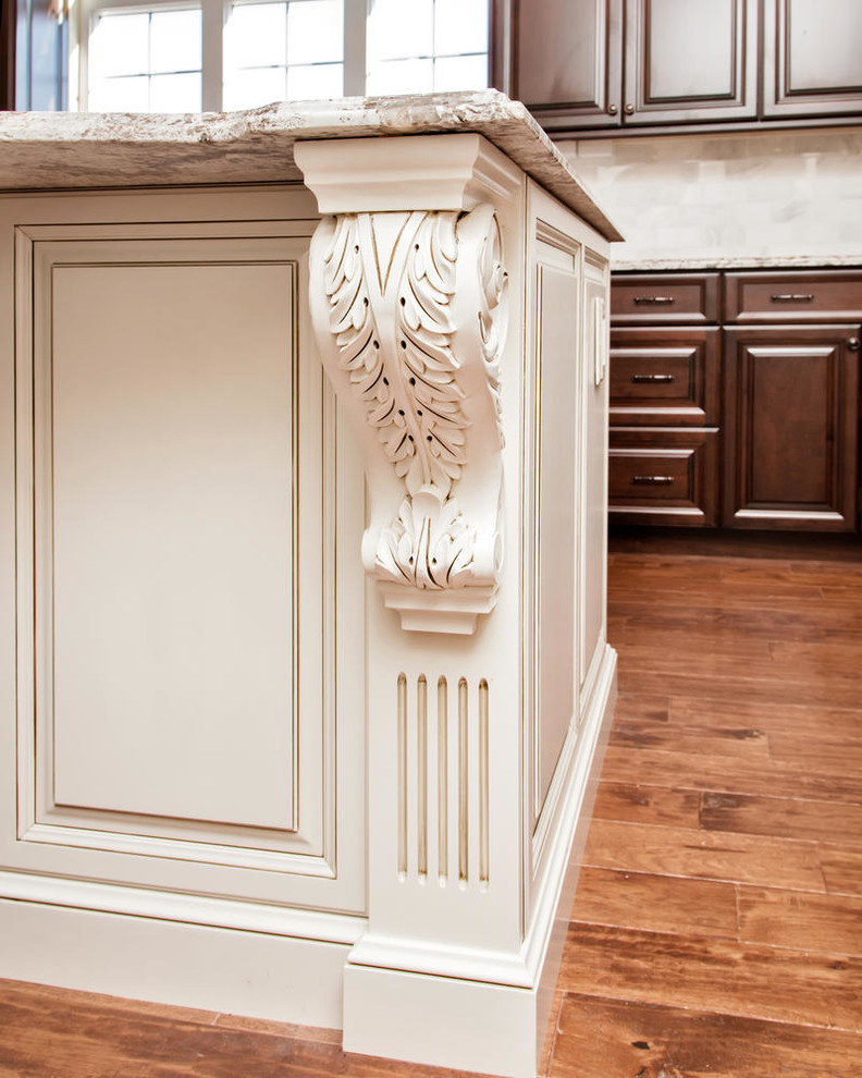 Klassisk inredning av ett stort kök, med en undermonterad diskho, luckor med upphöjd panel, bruna skåp, granitbänkskiva, vitt stänkskydd, stänkskydd i stenkakel, rostfria vitvaror, mellanmörkt trägolv och en köksö
