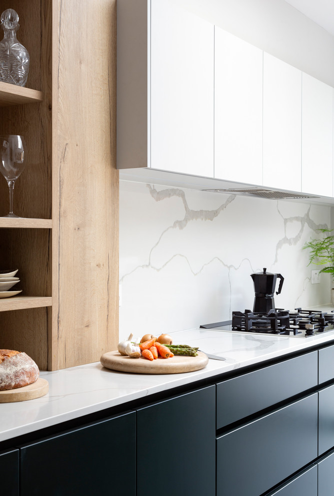 This is an example of a medium sized contemporary l-shaped open plan kitchen in London with an integrated sink, flat-panel cabinets, green cabinets, composite countertops, white splashback, marble splashback, stainless steel appliances, porcelain flooring, an island, grey floors and white worktops.