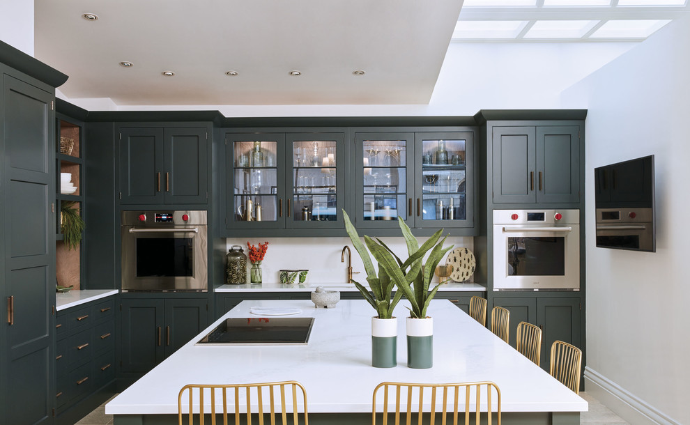 ロンドンにある中くらいなトランジショナルスタイルのおしゃれなキッチン (ドロップインシンク、シェーカースタイル扉のキャビネット、緑のキャビネット、珪岩カウンター、白いキッチンパネル、シルバーの調理設備、大理石の床、ベージュの床、白いキッチンカウンター) の写真