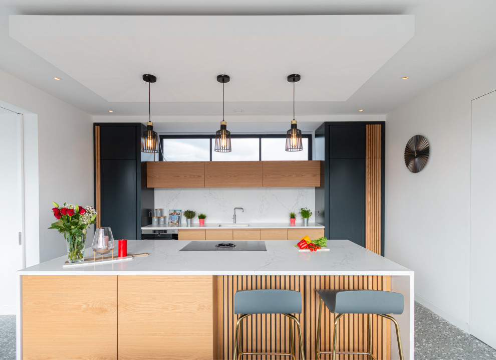 This is an example of a large contemporary galley kitchen in Other with a submerged sink, flat-panel cabinets, medium wood cabinets, white splashback, integrated appliances, an island, grey floors and white worktops.