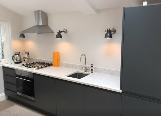 Mid-sized trendy single-wall open concept kitchen photo in London with a drop-in sink, flat-panel cabinets, gray cabinets, stainless steel appliances and an island