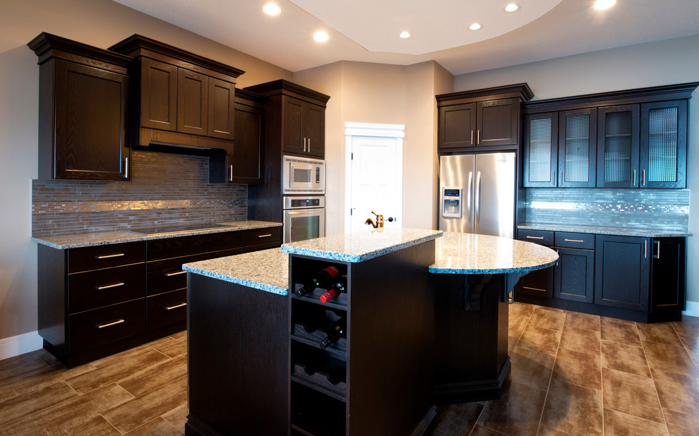 Eat-in kitchen - mid-sized contemporary u-shaped eat-in kitchen idea in Edmonton with an integrated sink, shaker cabinets, dark wood cabinets, granite countertops, gray backsplash, ceramic backsplash, stainless steel appliances and an island