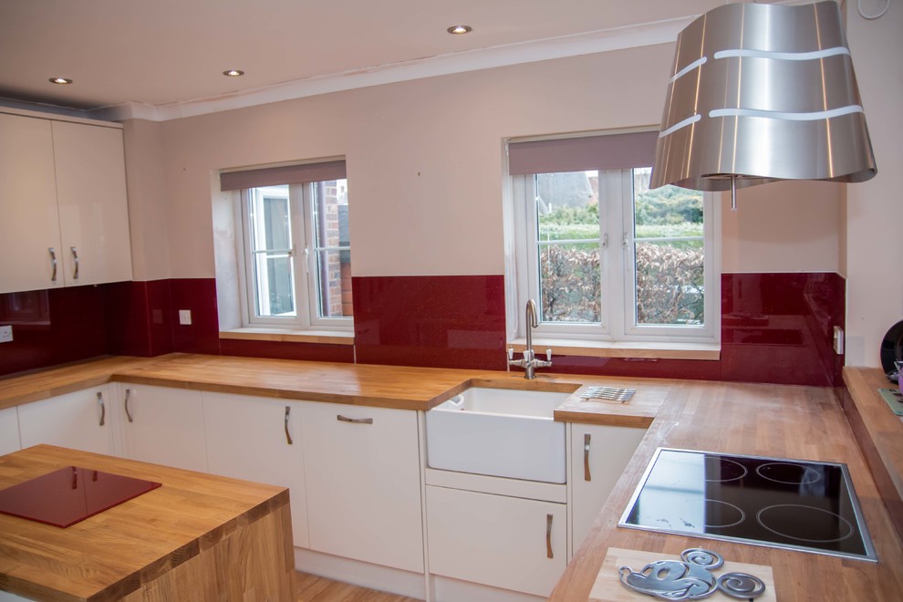 Cette image montre une cuisine avec une crédence rouge et une crédence en feuille de verre.