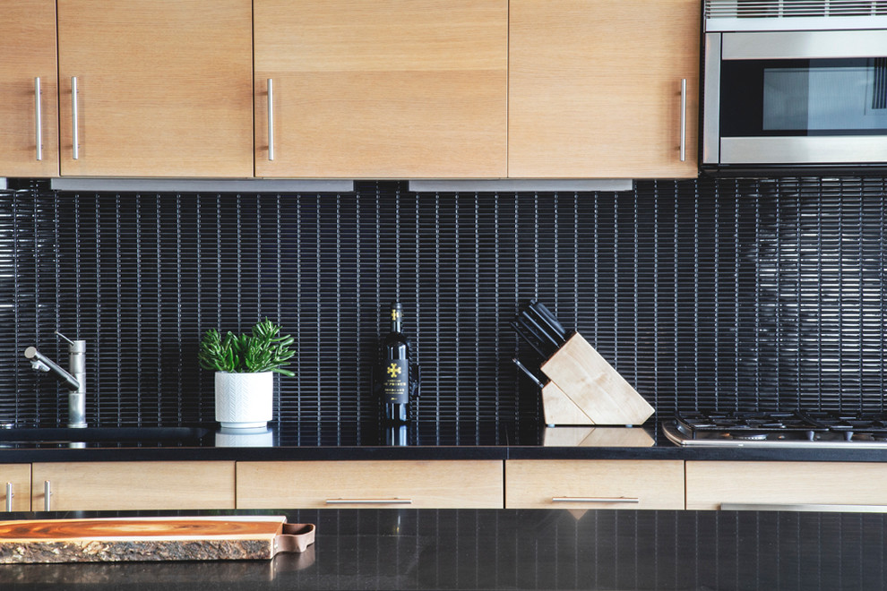 Inspiration för moderna linjära svart kök med öppen planlösning, med en nedsänkt diskho, skåp i ljust trä, bänkskiva i onyx, svart stänkskydd, stänkskydd i mosaik, rostfria vitvaror, klinkergolv i porslin, en köksö och grått golv