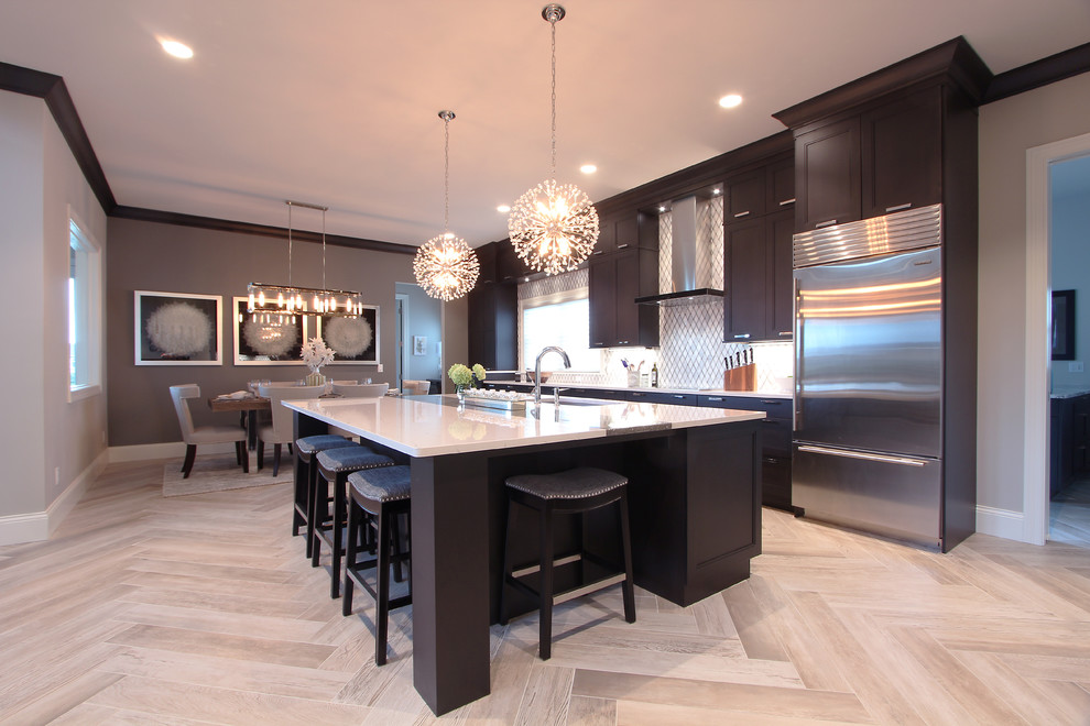 Example of a large transitional l-shaped light wood floor and brown floor open concept kitchen design in Other with an undermount sink, recessed-panel cabinets, dark wood cabinets, quartz countertops, white backsplash, marble backsplash, stainless steel appliances, an island and white countertops