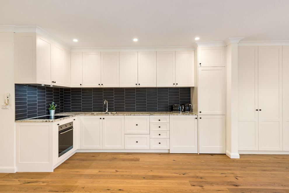 Einzeilige, Geräumige Moderne Wohnküche mit Unterbauwaschbecken, Schrankfronten im Shaker-Stil, weißen Schränken, Marmor-Arbeitsplatte und Küchenrückwand in Schwarz in Sydney