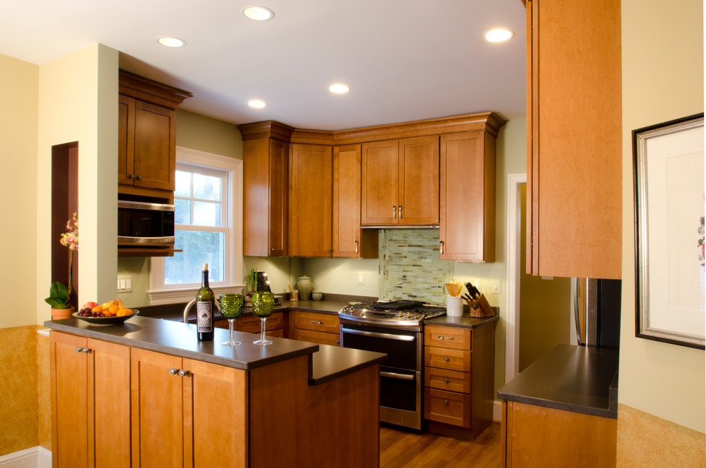 Small arts and crafts u-shaped medium tone wood floor eat-in kitchen photo in DC Metro with a farmhouse sink, shaker cabinets, medium tone wood cabinets, quartz countertops, green backsplash, glass tile backsplash, stainless steel appliances and a peninsula