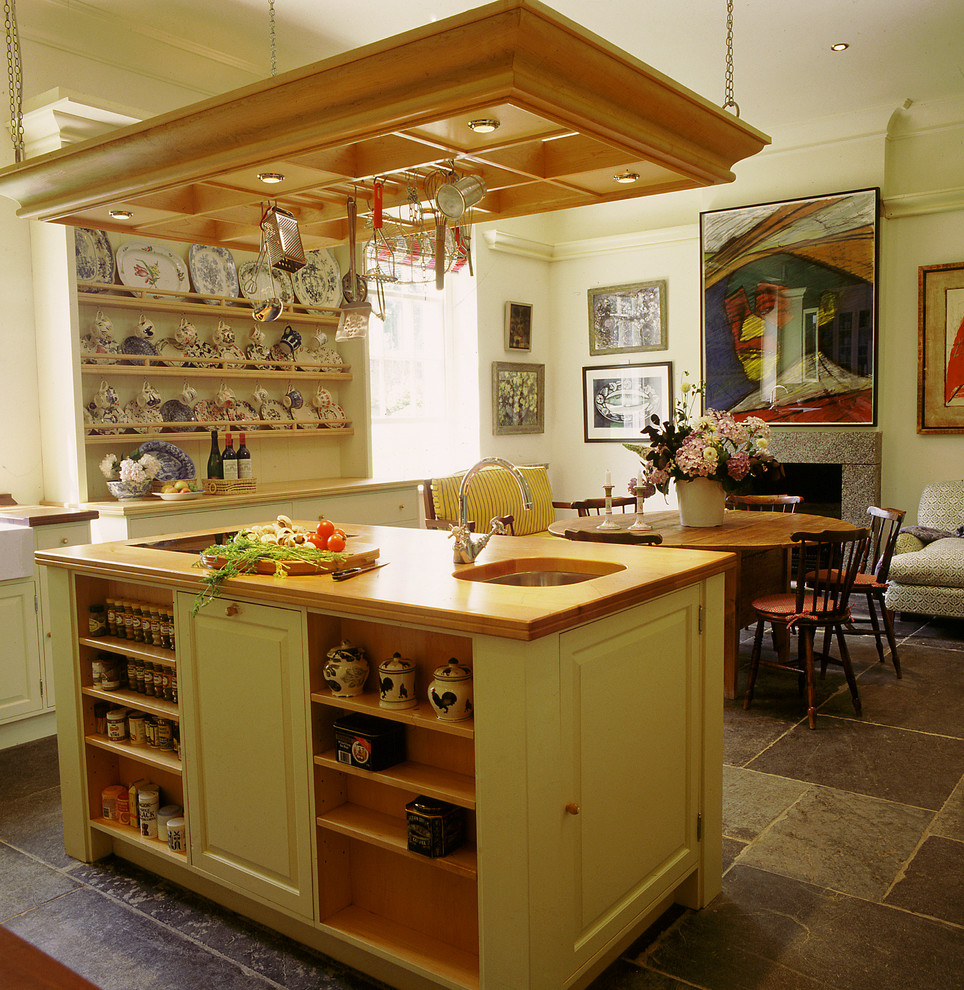 Klassisk inredning av ett stort vit vitt kök, med träbänkskiva, en rustik diskho, luckor med upphöjd panel, skiffergolv, en köksö och grått golv
