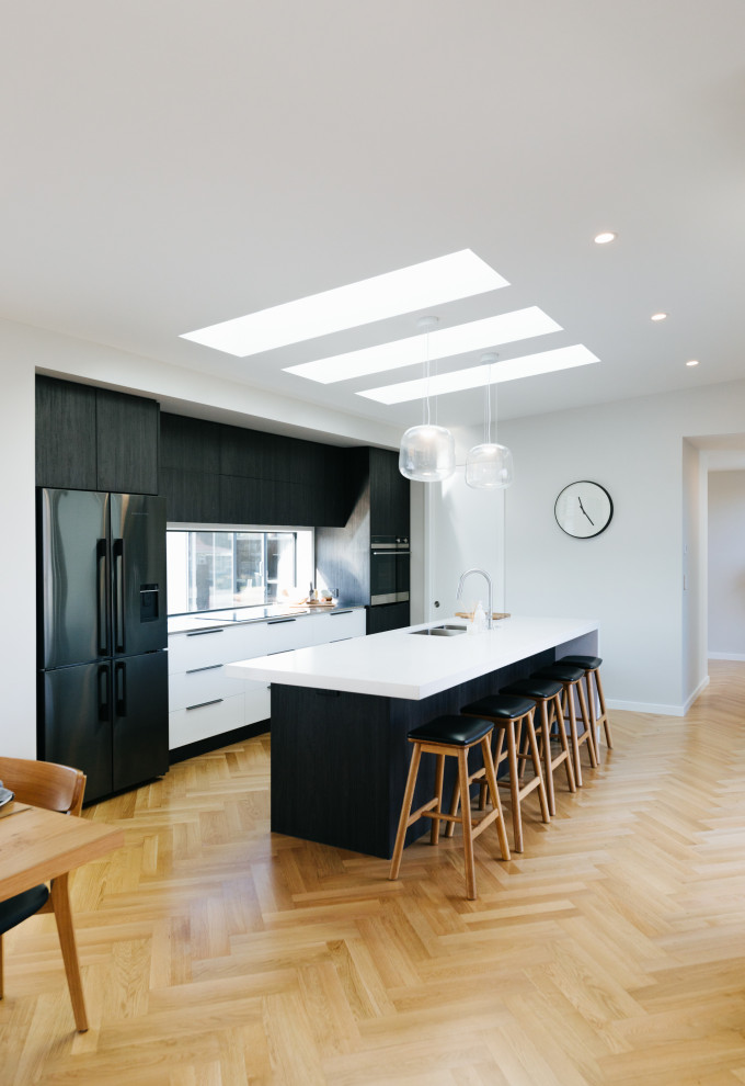 Esempio di una cucina minimalista di medie dimensioni con ante nere, pavimento in legno massello medio e pavimento beige