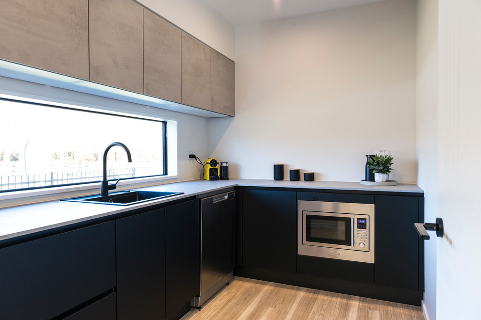 Immagine di una cucina moderna di medie dimensioni con lavello da incasso, ante lisce, ante nere, top in laminato, paraspruzzi bianco, paraspruzzi a finestra, elettrodomestici in acciaio inossidabile, pavimento in laminato e pavimento marrone