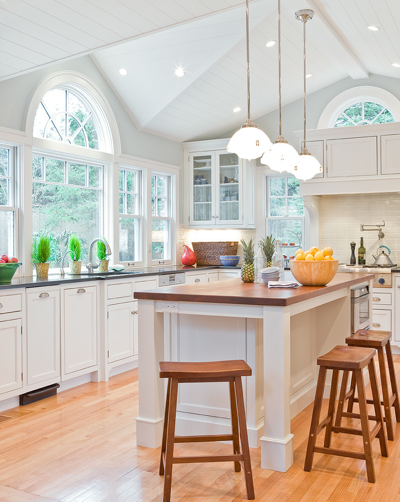 Elegant kitchen photo in Boston with beaded inset cabinets, wood countertops, white cabinets, white backsplash and subway tile backsplash
