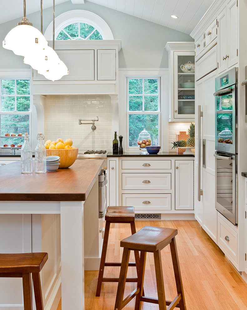 ボストンにあるトラディショナルスタイルのおしゃれなキッチン (インセット扉のキャビネット、パネルと同色の調理設備、サブウェイタイルのキッチンパネル、木材カウンター、白いキャビネット) の写真