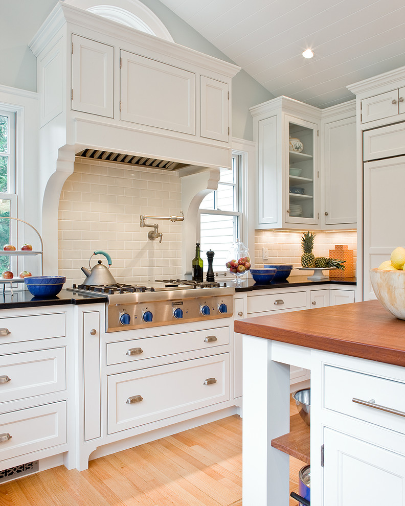 Photo of a classic kitchen in Boston with beaded cabinets, metro tiled splashback, wood worktops, white cabinets, white splashback and integrated appliances.