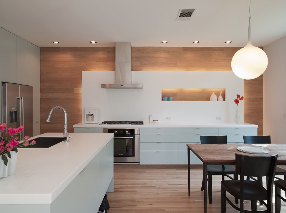 Moderne Wohnküche mit Küchengeräten aus Edelstahl, flächenbündigen Schrankfronten, blauen Schränken, Quarzwerkstein-Arbeitsplatte, Küchenrückwand in Weiß und Rückwand aus Stein in Austin