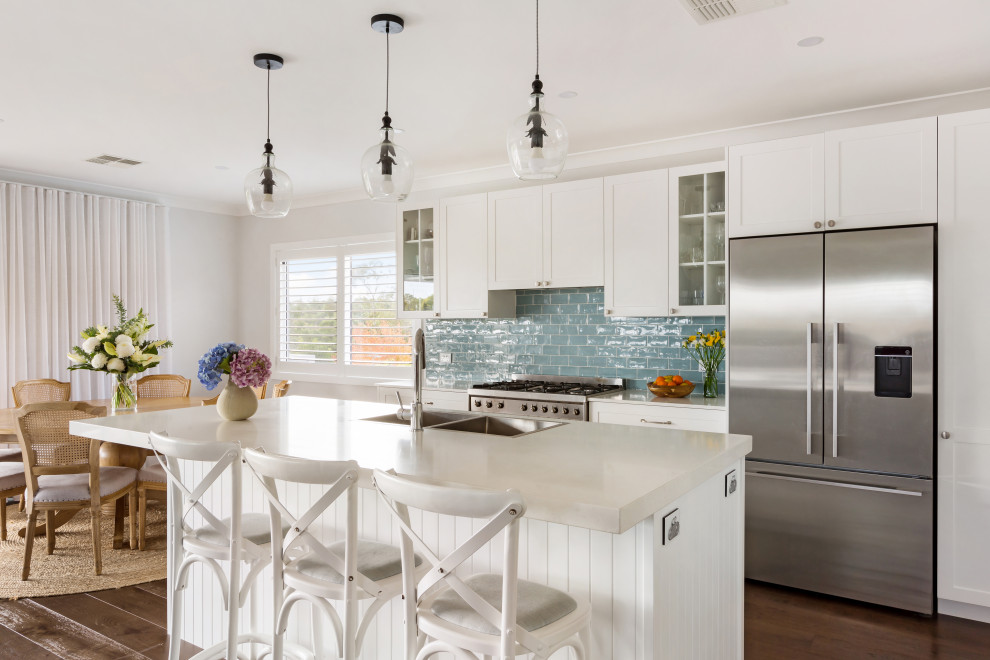 Transitional galley medium tone wood floor and brown floor eat-in kitchen photo in Sydney with a double-bowl sink, shaker cabinets, white cabinets, blue backsplash, subway tile backsplash, stainless steel appliances, an island and white countertops