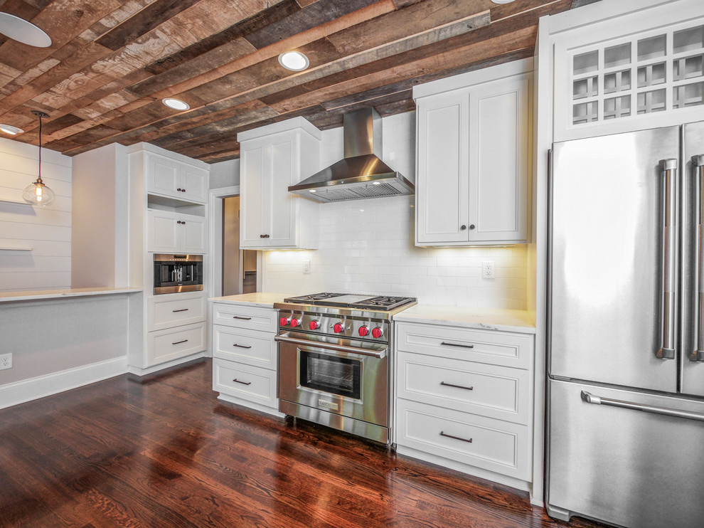 Foto på ett mellanstort 50 tals kök, med en rustik diskho, skåp i shakerstil, vita skåp, marmorbänkskiva, vitt stänkskydd, stänkskydd i keramik, rostfria vitvaror, mörkt trägolv och brunt golv