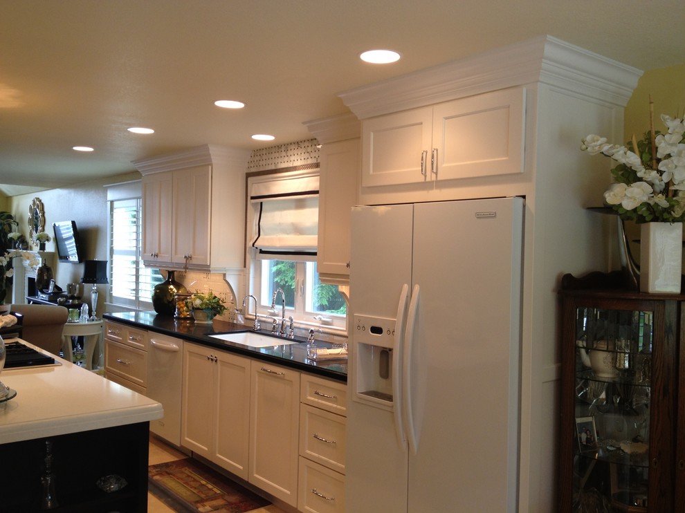 Example of a mid-sized classic galley travertine floor open concept kitchen design in Portland with an undermount sink, white cabinets, quartz countertops, white appliances and an island