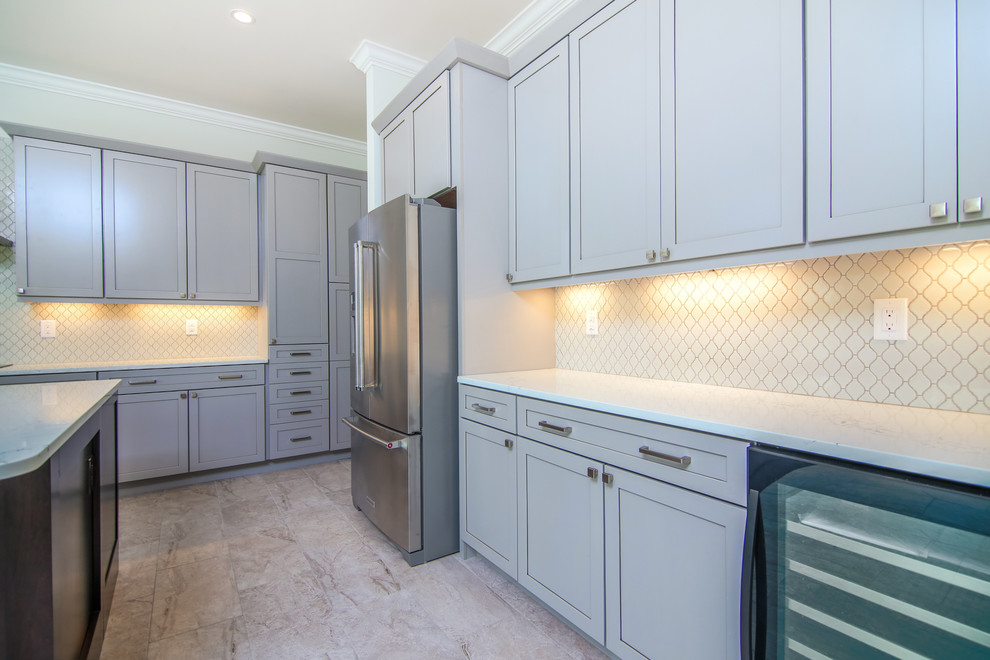 Inspiration for a large transitional l-shaped porcelain tile and gray floor eat-in kitchen remodel in Miami with a farmhouse sink, shaker cabinets, gray cabinets, quartz countertops, gray backsplash, porcelain backsplash, stainless steel appliances and an island