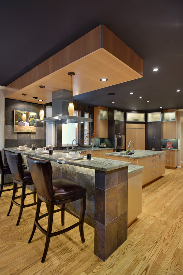 This is an example of a medium sized contemporary l-shaped enclosed kitchen in Sacramento with a submerged sink, flat-panel cabinets, light wood cabinets, granite worktops, grey splashback, stone tiled splashback, stainless steel appliances, light hardwood flooring and a breakfast bar.