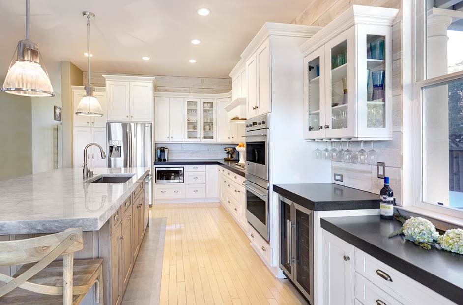 Mid-sized elegant l-shaped light wood floor eat-in kitchen photo in Sacramento with an undermount sink, shaker cabinets, white cabinets, quartzite countertops, white backsplash, mosaic tile backsplash, stainless steel appliances and an island