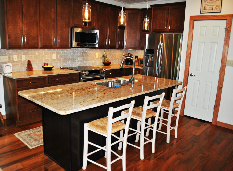 Mittelgroße Rustikale Küche mit Doppelwaschbecken, hellbraunen Holzschränken, Küchengeräten aus Edelstahl, braunem Holzboden, Kücheninsel und braunem Boden in Sonstige