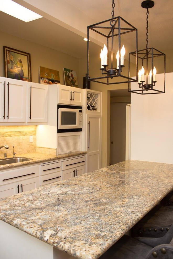 Modelo de cocina lineal tradicional renovada grande con fregadero encastrado, puertas de armario blancas, salpicadero beige, electrodomésticos con paneles y una isla