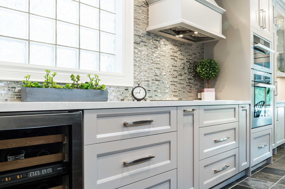 Example of a mid-sized transitional l-shaped porcelain tile and beige floor kitchen pantry design in Toronto with an undermount sink, shaker cabinets, gray cabinets, quartz countertops, white backsplash, mosaic tile backsplash, stainless steel appliances, an island and white countertops