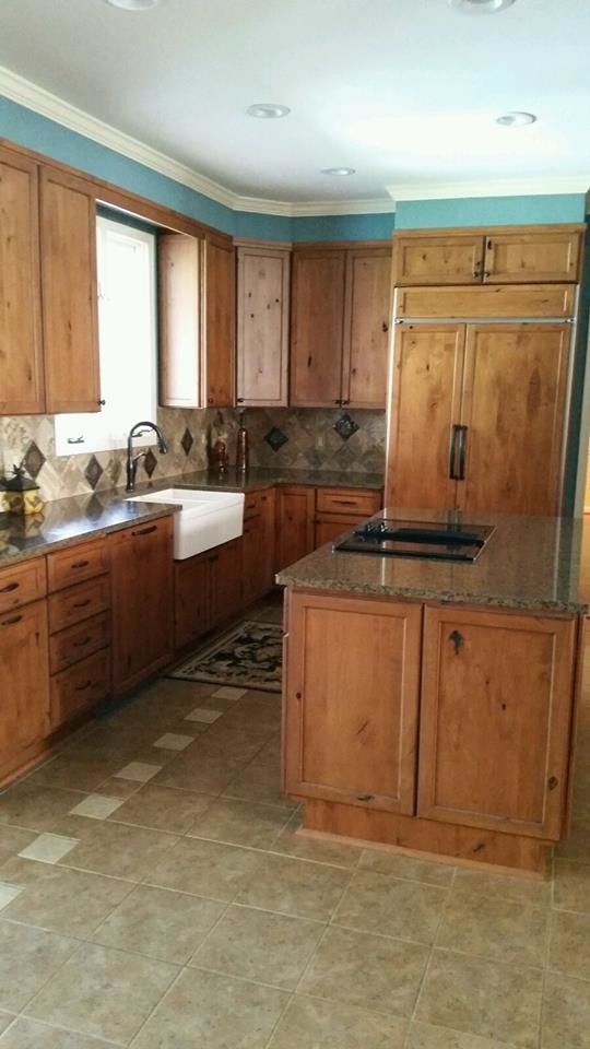 Bild på ett mellanstort vintage kök, med en rustik diskho, släta luckor, skåp i mellenmörkt trä, granitbänkskiva, grått stänkskydd, stänkskydd i keramik, integrerade vitvaror, klinkergolv i keramik, en köksö och brunt golv