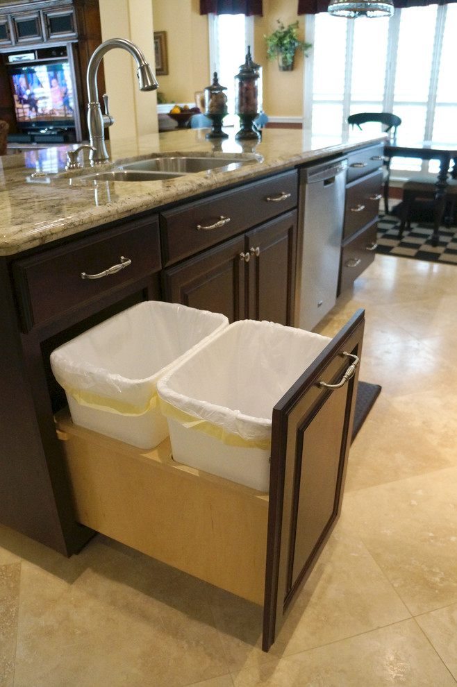 Mid-sized transitional travertine floor eat-in kitchen photo in Houston with a double-bowl sink, raised-panel cabinets, dark wood cabinets, granite countertops, beige backsplash, stone tile backsplash, stainless steel appliances and an island