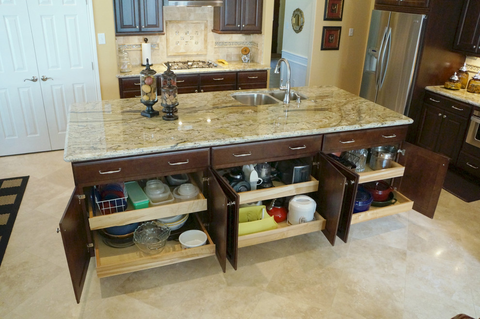 Eat-in kitchen - mid-sized transitional travertine floor eat-in kitchen idea in Houston with a double-bowl sink, raised-panel cabinets, dark wood cabinets, granite countertops, beige backsplash, stone tile backsplash, stainless steel appliances and an island